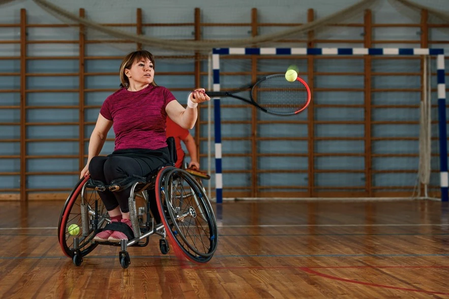Disabled woman in wheelchair playing indoor tennis