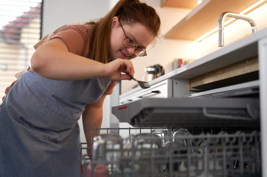 Disabled woman with down syndrome loading the dishwasher