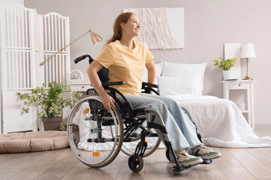 Disabled woman in wheelchair sitting in bedroom smiling