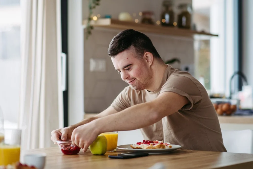 Disabled man with down syndrome making breakfast at kitchen table